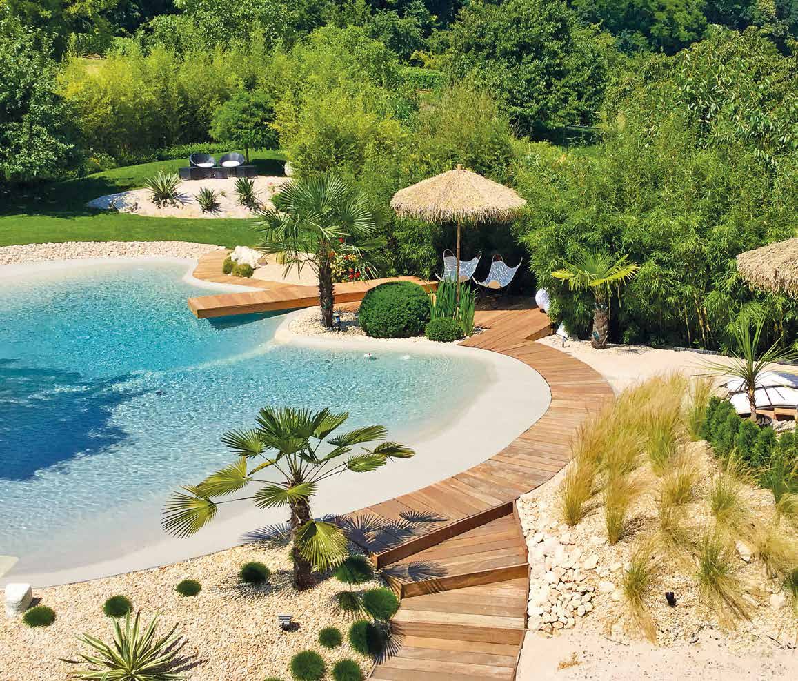 Piscina de arena Bio.design integrada en un jardín con solárium de madera